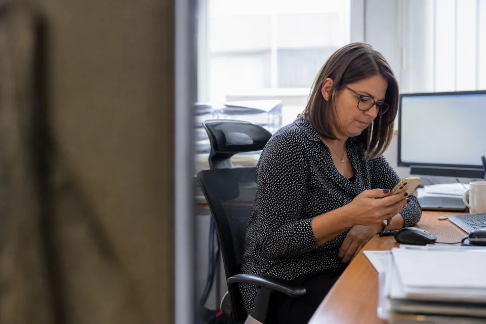Specjalistka do spraw finansów czyta powiadomienie na telefonie przy biurku