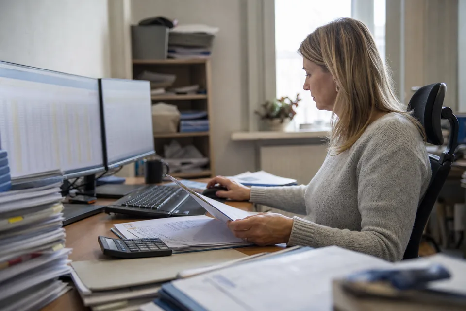Księgowa pracuje przy dwóch monitorach z tabelami w biurze rachunkowym